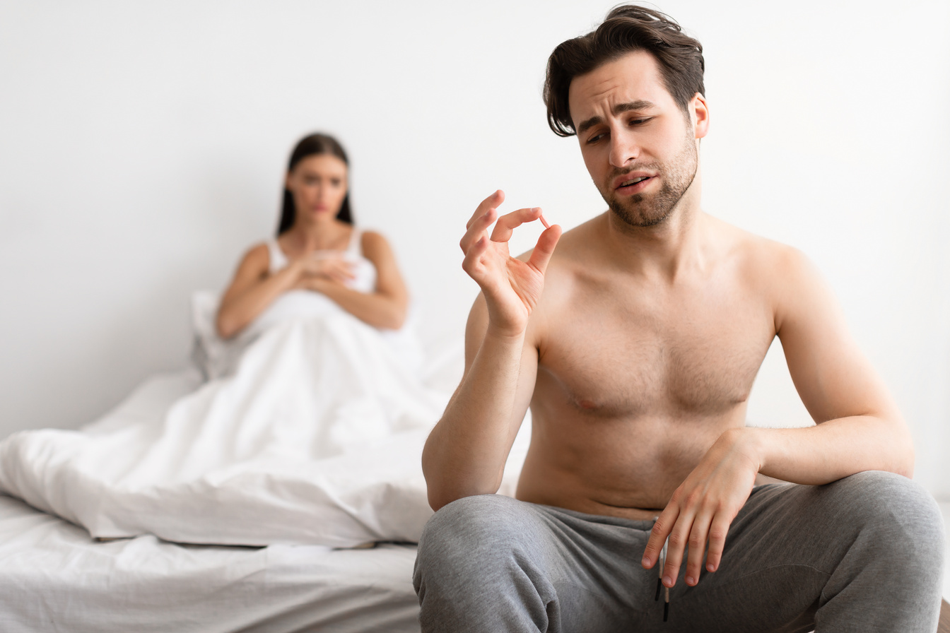 Man Holding Potency Pill While Girlfriend Waiting For  Indoor